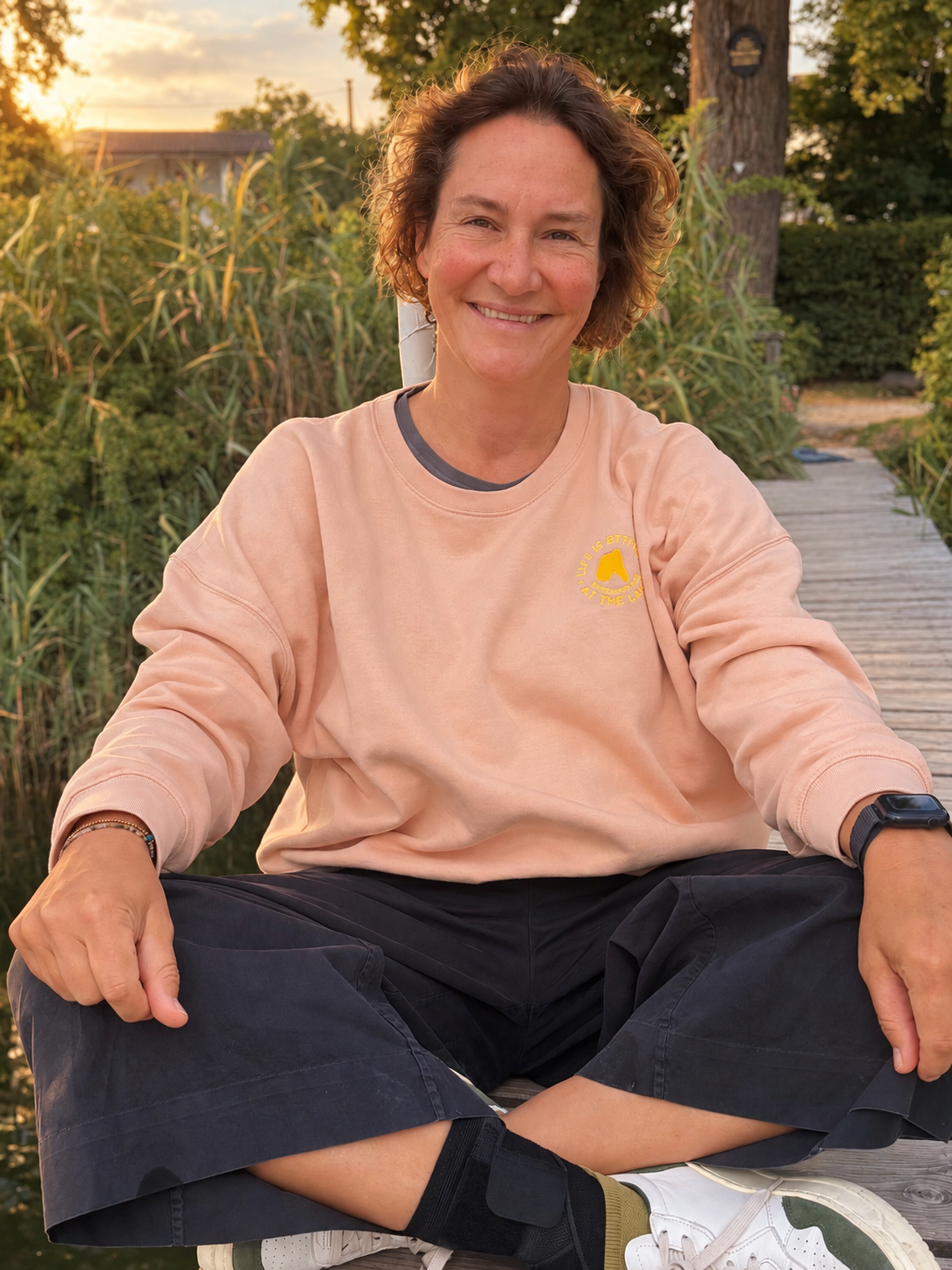 Lena, Gründerin von SEEVIBES, sitzt lachend auf einem Steg am See